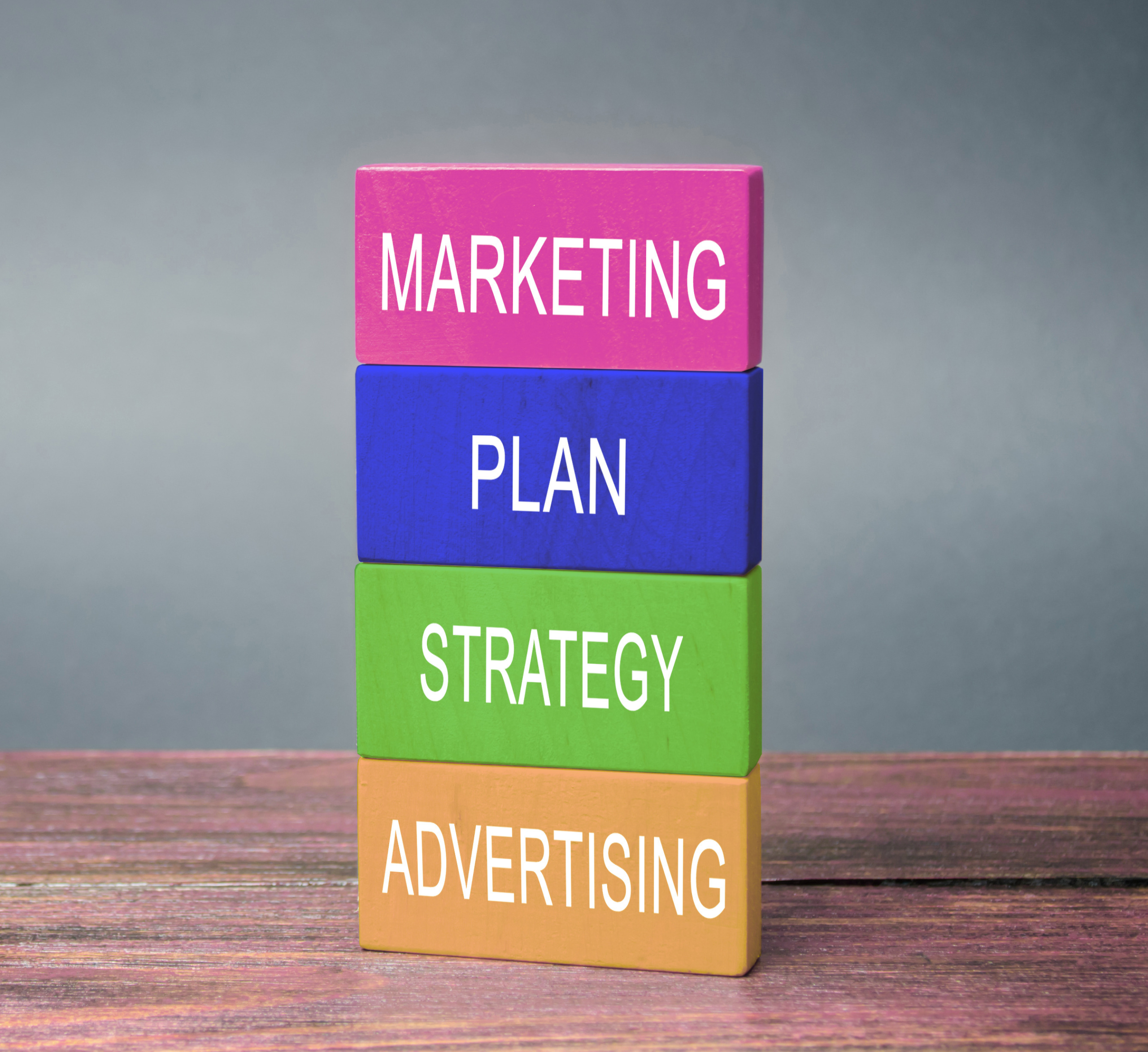 Stacked blocks labeled marketing, plan, strategy, and advertising, representing the structure of a marketing plan that supports revenue
