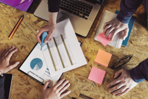 Team reviewing reports, notes, and planning documents during a sales and marketing workflow improvement meeting