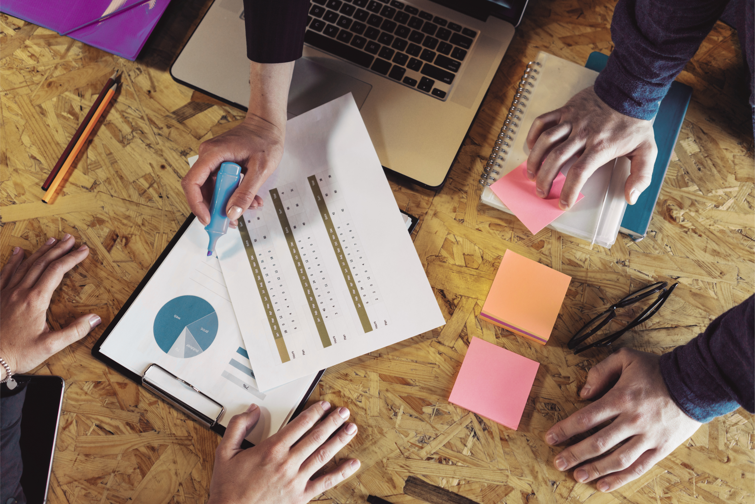 Team reviewing reports, notes, and planning documents during a sales and marketing workflow improvement meeting