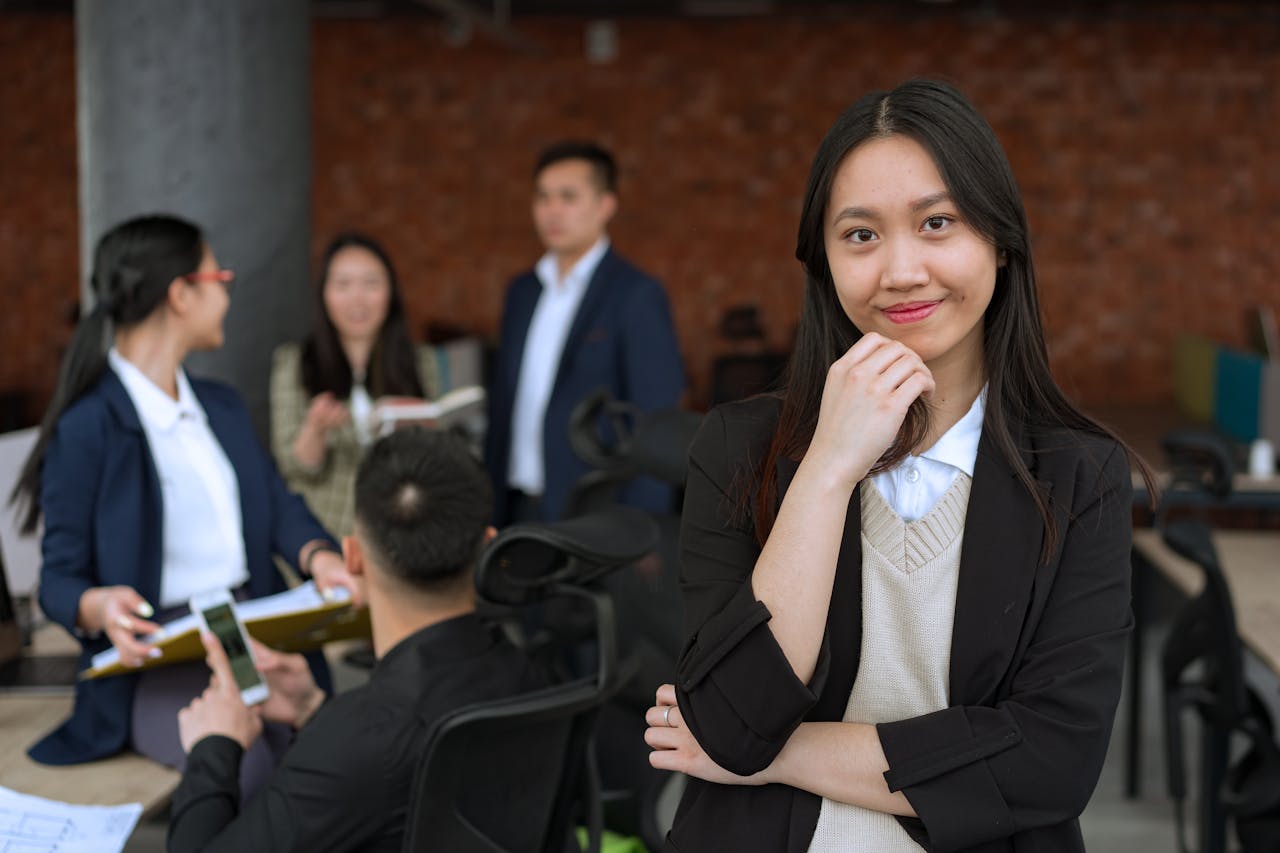 Marketing professional standing in an office while team members collaborate in the background on a small business marketing strategy