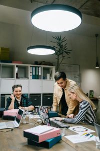 Team members reviewing laptops and printed charts during a small business marketing meeting in a modern office