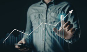 Person pointing to an upward growth chart representing sales and marketing process improvement and stronger revenue performance.